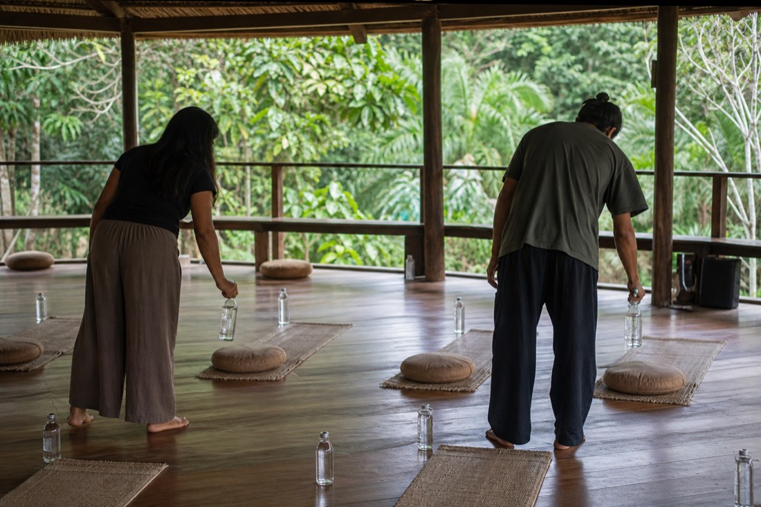 Two facilitators preparing a ceremony space in daylight, arranging mats and water bottles
