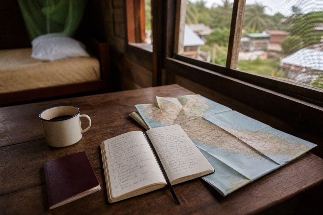 Traveler's notebook and map of Peru on a guesthouse table, shortlisting ayahuasca retreat options